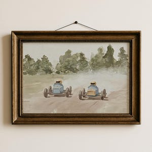 May include: An oil painting in a gold frame depicts two vintage race cars speeding down a dirt track. The cars are light blue with drivers wearing yellow helmets. The background features a green forest and a hazy sky.
