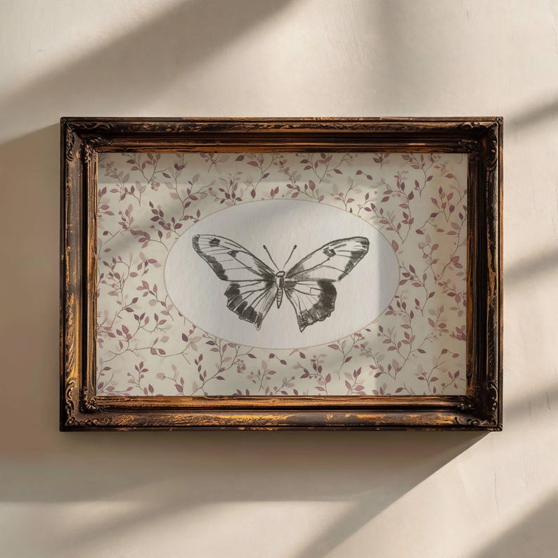 May include: A framed print of a black and white butterfly on a white background with a floral pattern. The frame is brown wood with a distressed finish.