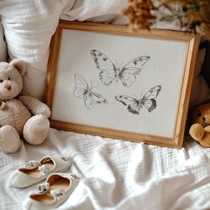 Puede incluir: Una impresi&oacute;n enmarcada con fondo blanco y tres ilustraciones de mariposas en blanco y negro. Las mariposas est&aacute;n dibujadas en un estilo vintage.