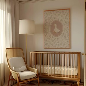 Puede incluir: Una cuna blanca con un colch&oacute;n blanco y una l&aacute;mpara blanca con una pantalla beige. Una silla de mimbre con un coj&iacute;n blanco se encuentra en la esquina de la habitaci&oacute;n. Una impresi&oacute;n enmarcada con una ilustraci&oacute;n de un pato cuelga de la pared.