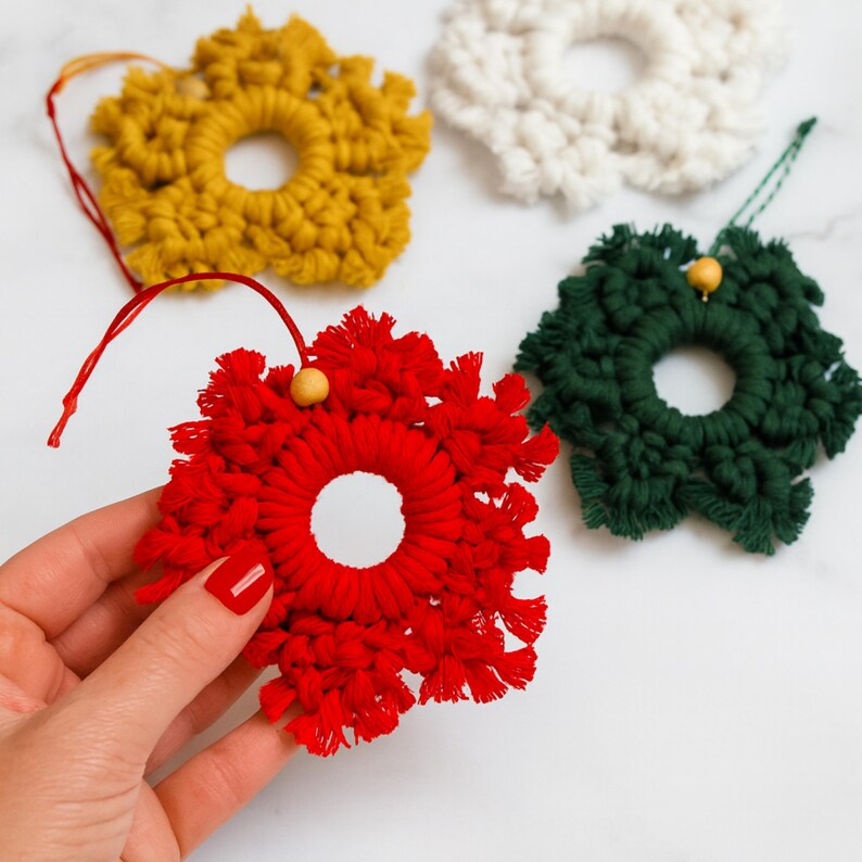 Finished red macrame snowflake ornament held in a hand, showing the detailed knotted cord design and handmade texture of this Christmas decoration.