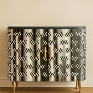 May include: A cabinet with a geometric black and cream pattern. The cabinet has two doors with gold handles and sits on gold legs. The top of the cabinet is black.
