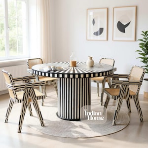 May include: A round dining table with a black and white striped design, surrounded by four chairs. The chairs have a woven back and armrests, with a black and white geometric pattern. The table is approximately 122 cm in diameter.
