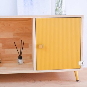 Yellow fluted media console with solid wood body and gold metal legs in modern living room
