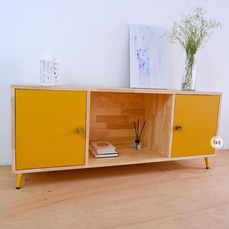 Aura yellow media console with fluted doors, gold knobs, and open shelf storage