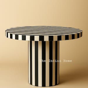 May include: A round side table with a black and white striped top and a cylindrical base. The base is also black and white striped. The text "The Indian Home" is printed on the base.