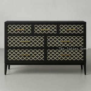 Könnte beinhalten: Schwarze Kommode mit sechs Schubladen, die jeweils ein geometrisches Muster aus weißen Halbkreisen auf der Front haben. Die Kommode hat goldfarbene Griffe.