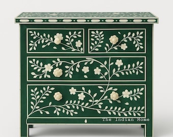 May include: A dark green chest of drawers with four drawers, adorned with white floral and vine inlay. The chest features white flower-shaped knobs and a decorative border on the top. The text "The Indian Home" is visible on the bottom right.