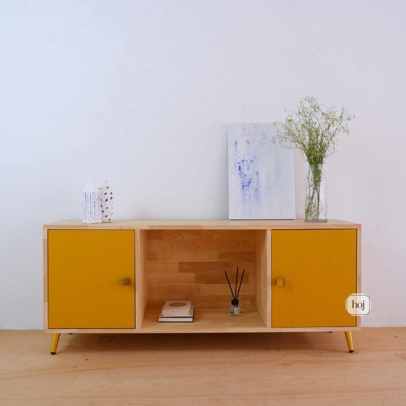 Aura yellow media console with fluted doors, gold knobs, and open shelf storage