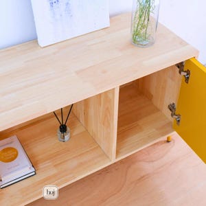 Aura yellow media console with fluted doors, gold knobs, and open shelf storage