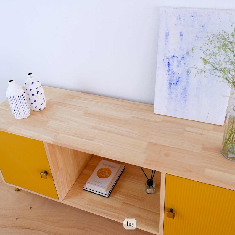 Aura yellow media console with fluted doors, gold knobs, and open shelf storage