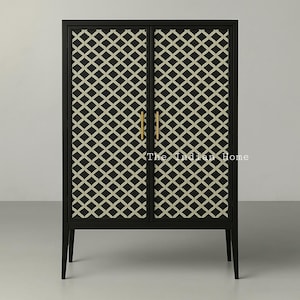 Könnte beinhalten: Ein schwarzer Schrank mit zwei Türen, die mit einem geometrischen Muster verziert sind. Die Türen haben goldene Griffe. Der Schrank hat vier schwarze Beine.