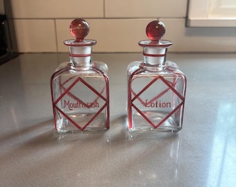 Vintage glass bottles labeled mouthwash and lotion with red design and glass toppers for unique bathroom design