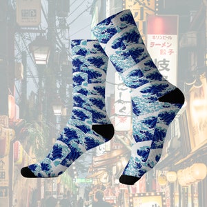 May include: A pair of crew socks featuring a repeating pattern of blue and white ocean waves. The socks have black heels and toes. The design is inspired by Japanese art and culture.