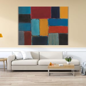 Peut inclure: Tableau abstrait avec un motif en patchwork de formes rectangulaires aux couleurs vives : rouge, bleu, jaune et noir. L'œuvre est accrochée au-dessus d'un canapé blanc dans un salon. Le tableau apporte une touche de couleur à la décoration.