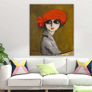 Può includere: Un dipinto a olio di una donna con un cappello rosso e un cappotto grigio. La donna ha occhi scuri e labbra rosse. Lo sfondo è di colore giallo-marrone tenue. Il dipinto è esposto sopra un divano bianco con cuscini colorati.