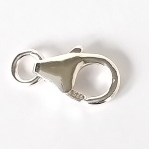 May include: Silver lobster clasp with a spring ring closure. The clasp is marked with "925" indicating sterling silver.