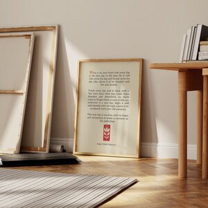 May include: A framed print with a white background and black text. The text is a quote by Ralph Waldo Emerson about living in the present moment. The quote is surrounded by a red border and a small red flower graphic.