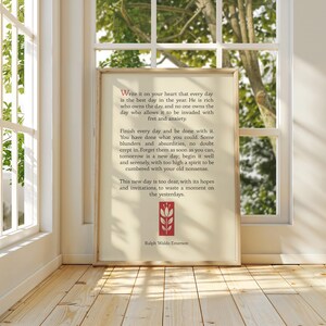 May include: A framed print with a white background and red text. The text is a quote by Ralph Waldo Emerson about living in the present moment. The quote reads: "Write it on your heart that every day is the best day in the year. He is rich who owns the day, and no one owns the day who allows it to be invaded with fret and anxiety. Finish every day and be done with it. You have done what you could. Some blunders and absurdities, no doubt crept in. Forget them as soon as you can, tomorrow is a new day; begin it well and serenely, with too high a spirit to be cumbered with your old nonsense. This new day is too dear, with its hopes and invitations, to waste a moment on the yesterdays."