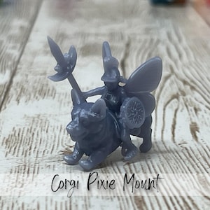 May include: A gray miniature figurine of a corgi ridden by a pixie with a shield and a spear-like weapon. The figurine has fairy wings and is labeled "Corgi Pixie Mount" in cursive text.