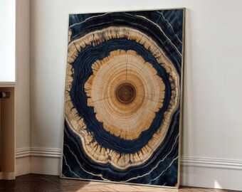 May include: A framed artwork featuring a cross-section of a tree trunk. The artwork showcases concentric rings in shades of tan and brown, surrounded by a dark blue, almost black, outer layer. The piece is leaning against a white wall.