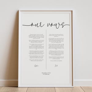 May include: Framed print featuring wedding vows in elegant script. The text is divided into two columns, with the words "our vows" at the top. Names and a date are at the bottom. The frame is white.