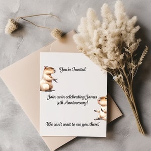 May include: A white card with a black border and text that reads "You're Invited" and "Join us in celebrating James 5th Anniversary! We can't wait to see you there!"  Two cartoon capybaras are on the card, one on each side of the text.