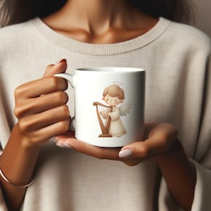 May include: White ceramic mug with a cartoon illustration of an angel playing a harp. The angel has a halo and is wearing a white robe.