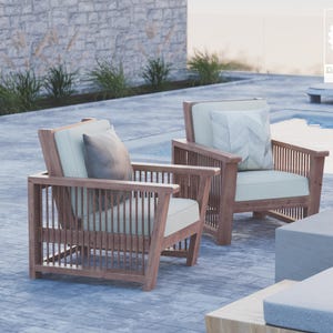 May include: Two wooden chairs with light beige cushions and a brown pillow on each chair. The chairs are positioned on a gray concrete patio near a swimming pool.