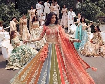 Könnte beinhalten: Ein mehrfarbiger Lehenga Choli mit einem Bahnenrock in Orange-, Grau- und Olivgrüntönen, verziert mit aufwendigen weißen Stickereien und Goldperlen. Das Set umfasst eine passende bestickte Bluse und einen transparenten orangefarbenen Dupatta.