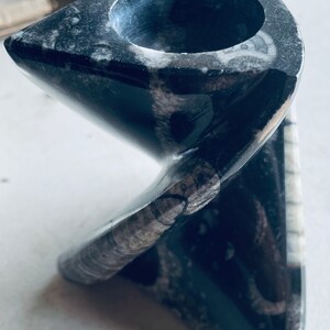 Peut inclure: Un bougeoir en pierre fossilisée en forme de spirale noir et blanc. Le bougeoir a une ouverture ronde au sommet pour une bougie.