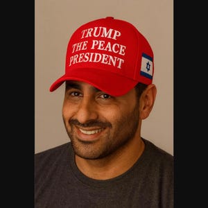 Puede incluir: Una gorra de b&eacute;isbol de color rojo brillante con el texto bordado en blanco TRUMP THE PEACE PRESIDENT en la parte frontal. El lateral de la gorra muestra un peque&ntilde;o parche rectangular con la bandera azul y blanca de Israel, con la Estrella de David.