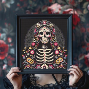 May include: A black framed picture with a colorful Day of the Dead sugar skull illustration. The skull is wearing a black veil with floral embroidery. The background is a dark floral pattern.