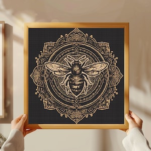 May include: A gold bee mandala design on a black background. The bee is in the center of the mandala and has a detailed design. The mandala is surrounded by a black frame.