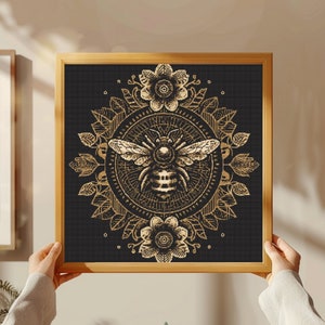 May include: A gold bee with wings outstretched is surrounded by a mandala of gold flowers and leaves on a black background. The bee is in the center of the mandala, which is surrounded by a black border.