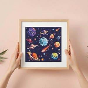 May include: A framed cross-stitch design featuring a colourful depiction of planets and stars in a dark blue space. The planets are various sizes and colours, including red, orange, yellow, blue, and green.