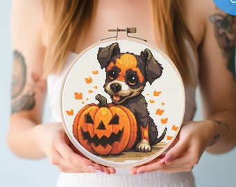 May include: Cross stitch pattern featuring a cute cartoon dog with brown and white fur holding a jack-o'-lantern pumpkin. The pattern is in a round hoop and is ready to be stitched.