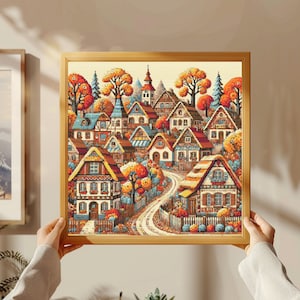 May include: A framed cross-stitch artwork depicting a quaint village nestled in a colorful autumnal landscape. The houses are adorned with intricate details and surrounded by vibrant foliage.
