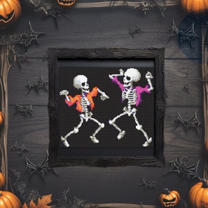 May include: Two skeletons in a black frame, dancing with their arms raised. The skeleton on the left is wearing an orange shirt and the skeleton on the right is wearing a pink shirt. The background is a dark wood grain.
