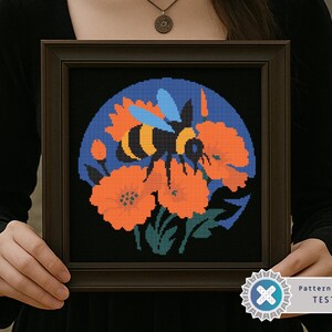 May include: Framed cross-stitch art featuring a bee and orange flowers against a blue background. The bee has black and yellow stripes. The artwork is in a dark brown frame. The image is labeled "Pattern Keeper TESTED".