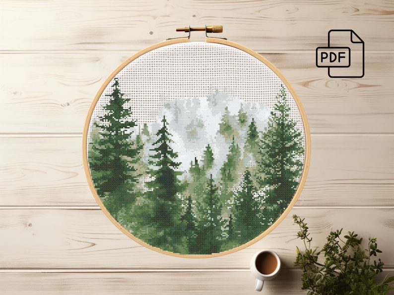 May include: A cross-stitch pattern of a forest scene with tall green trees and a white, foggy background. The pattern is displayed in a round wooden embroidery hoop.