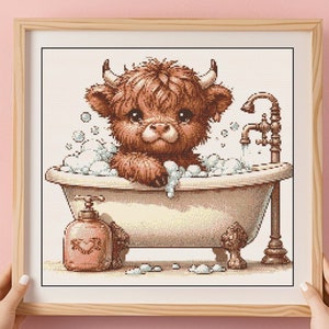 Può includere: Una mucca Highland marrone e bianca che fa il bagno in una vasca da bagno bianca con bolle. La mucca ha il naso rosa e guarda lo spettatore. C'è un rubinetto dorato e una bottiglia di sapone con un cuore.