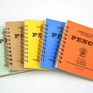 May include: Five composition notebooks with different colored covers. The covers are green, brown, yellow, blue, and orange. The notebooks are all spiral bound and have the word "PENCO" printed on the front. The orange notebook has the text "COMPOSITION NOTEBOOK" and "3 1/2 x 4 1/2, 80 SHEETS, 7mm RULED, COLLEGE RULED HIGH GRADE SELECTED PAPER, MADE IN JAPAN" printed on the front.
