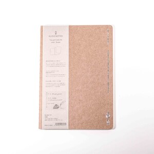 K&ouml;nnte beinhalten: Ein beigefarbenes Notizbuch mit einem Papieretikett auf der linken Seite. Das Etikett enth&auml;lt Text und Illustrationen auf Japanisch und Englisch. Das Notizbuch ist geschlossen und hat ein minimalistisches Design. Das Notizbuch befindet sich auf wei&szlig;em Hintergrund.