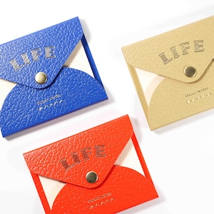 May include: Three small pouches in blue, beige, and red. Each pouch has a flap with the word "LIFE" embossed, and a gold snap closure. The pouches are likely for small items, such as coins or notes.