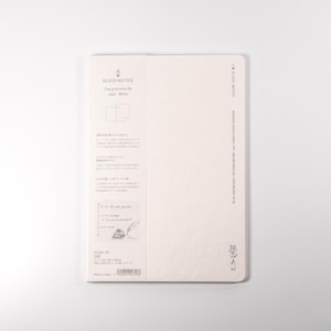 K&ouml;nnte beinhalten: Ein cremefarbenes Notizbuch mit dem Text "ALBUM NOTES" und japanischem Text. Das Notizbuch hat ein Rastermuster und ist offen, um leere Seiten zu zeigen. Die R&uuml;ckseite des Notizbuchs hat gedruckten Text und einen Barcode.