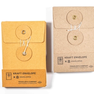 May include: Two kraft paper envelopes with string closures. One is a darker shade of brown, and the other is a lighter shade. Each envelope has a circular closure with a brass grommet. The text "KRAFT ENVELOPE x 8 ENVELOPES" is printed on the front.