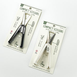 May include: Two packages of small, black and white pocket scissors. The packaging is white with black and green text that reads "XS Compact Scissors とても小さい! ハサミ".