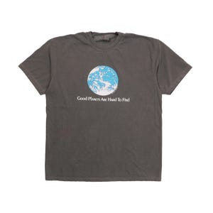 Peut inclure: Un t-shirt gris anthracite à manches courtes orné d'un motif circulaire représentant la Terre dans des tons bleu et blanc. Sous le graphique, le texte "Good Planets Are Hard To Find" est inscrit en lettres blanches centrées sur la poitrine.