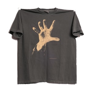 May include: A dark gray t-shirt with a large, faded, tan hand print on the front.
